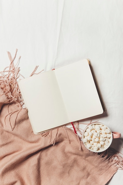 un cuaderno y café con una manta caliente sobre la ropa de cama blanca Desayuno en la cama