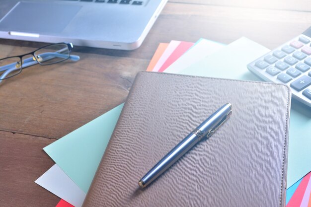 Foto cuaderno con calculadora, teclado y bolígrafo en la mesa