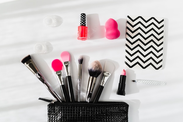 Foto cuaderno cerca de la bolsa de maquillaje con cosméticos