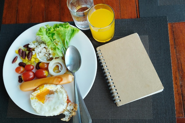 Cuaderno con desayuno en mesa de madera