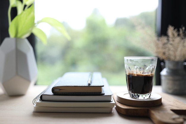 Cuaderno diario y taza de café en una mesa de madera con vista a la ventana