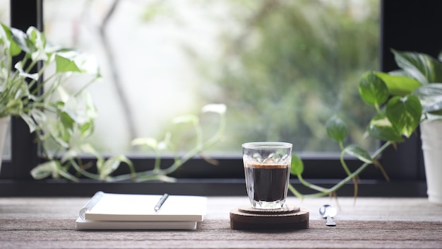 Cuaderno diario y taza de café en una mesa de madera con vista a la ventana