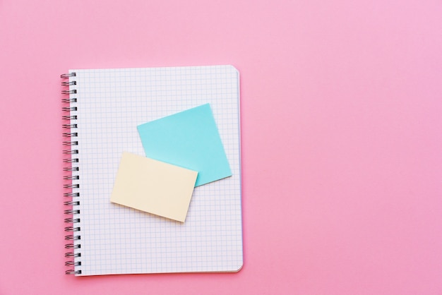 Cuaderno espiral escolar sobre un fondo rosa pegatinas se encuentran en la parte superior de la hoja de papelería para notas y ...