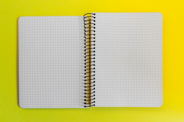 Cuaderno espiral de papel en blanco sobre amarillo