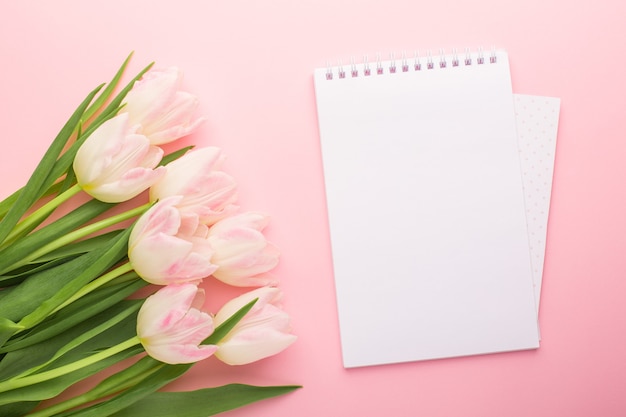 Cuaderno y flor de primavera tulipanes rosados en el rosa