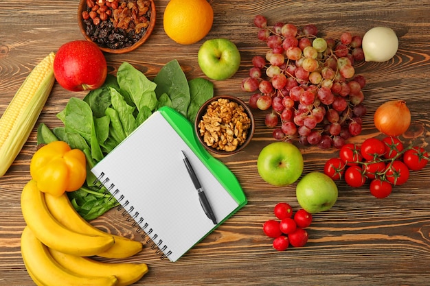 Foto cuaderno con frutas y verduras sobre fondo de madera