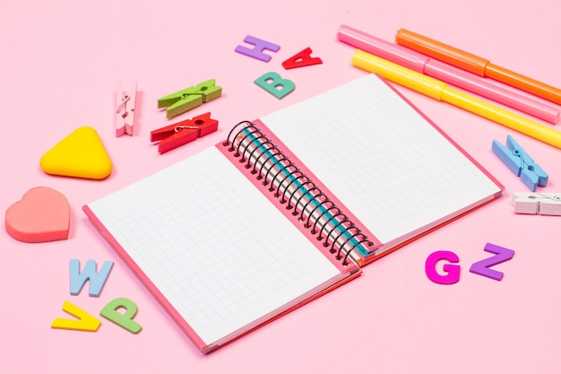 Cuaderno gráfico abierto y utensilios escolares sobre un fondo rosa