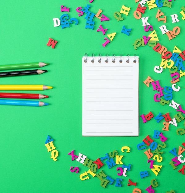 Cuaderno con hojas blancas vacías y lápices de madera multicolores.