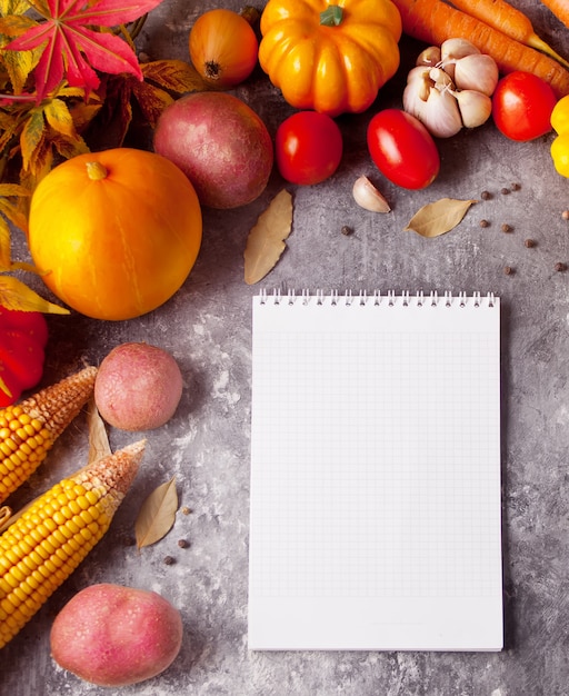 Cuaderno con hojas de otoño y verduras en el fondo de hormigón