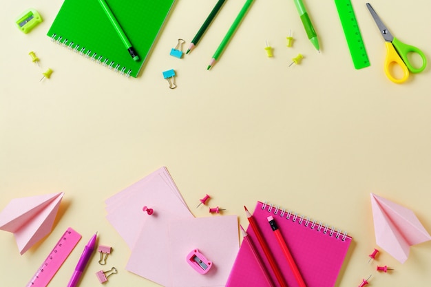 Cuaderno, lápices de colores, regla, bolígrafo, borrador, sacapuntas y papelería escolar y de oficina sobre fondo amarillo.