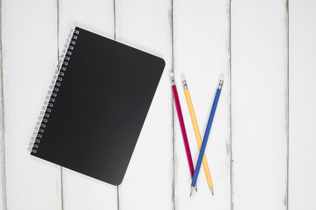 Cuaderno y lápiz del color negro en la tabla. Idea y concepto de la oficina de escritorio de la señora.