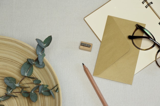 El cuaderno, lápiz de madera y sacapuntas, sobre, gafas, ramas de eucalipto en la cesta.