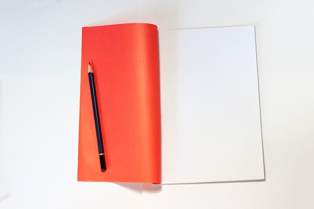 un cuaderno con un lápiz sobre un fondo blanco un espacio de trabajo para estudiar