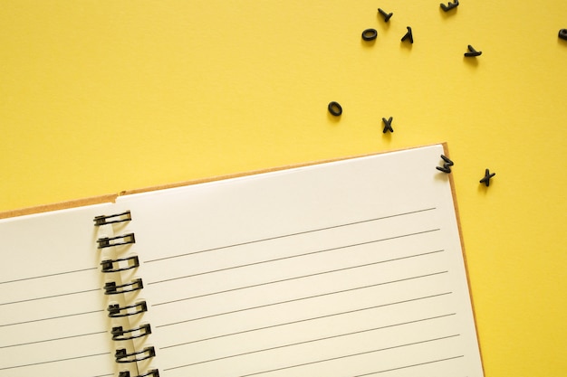 Cuaderno y letras negras 3d sobre fondo amarillo