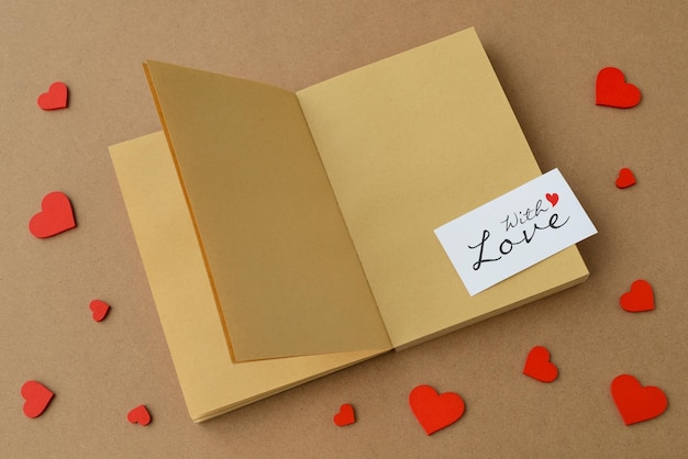 Foto cuaderno de libro abierto hecho de tarjeta de papel kraft con amor y corazones rojos en la mesa tarjeta del día de san valentín