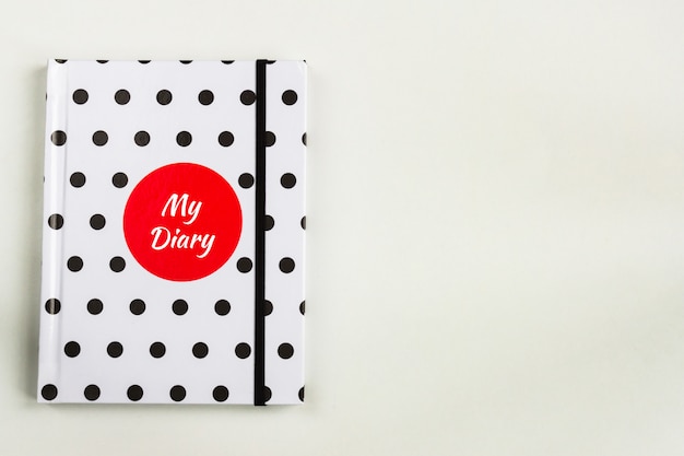 Cuaderno de lunares en blanco y negro con círculo rojo y mi inscripción de diario en la portada.