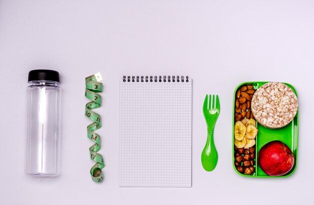 Cuaderno, manzana, nueces, chips de plátano, panecillos en un recipiente de comida