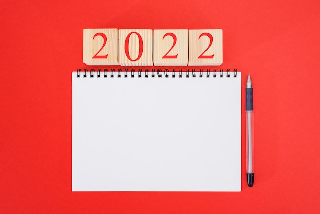 Cuaderno de maqueta 2022 sobre fondo rojo. Año nuevo. planes para 2022, lugar para texto en el bloc de notas, maqueta de calendario