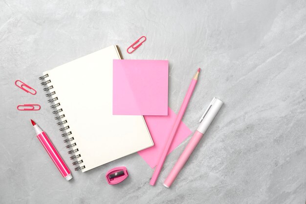 Foto cuaderno y nota adhesiva rosa y papelería en fondo de textura de piedra espacio de escritorio de trabajo