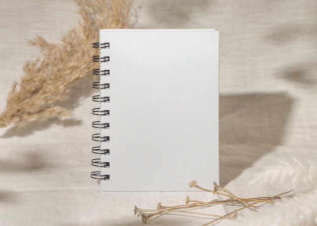 Cuaderno de notas en espiral gris cerca de la hierba de la pampa beige en lino maqueta de primer plano de papelería de boda bohemia
