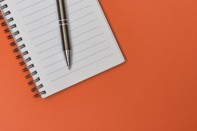 Un cuaderno con una página en blanco y un bolígrafo sobre él.