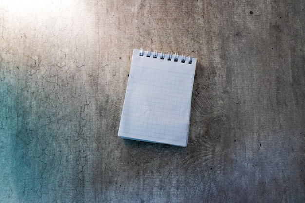 Un cuaderno con una página en blanco se encuentra sobre un fondo gris. Copie el espacio, el diseño, la maqueta.