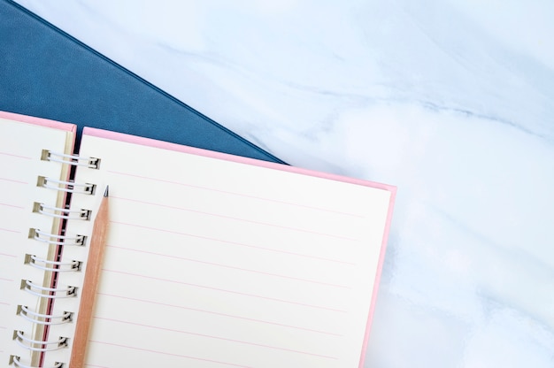 Cuaderno de la página en blanco y lápiz en la mesa de mármol blanco