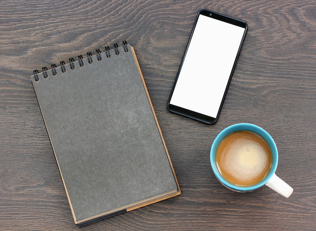 Cuaderno de papel en blanco con una página en negro, teléfono inteligente con una pantalla legible