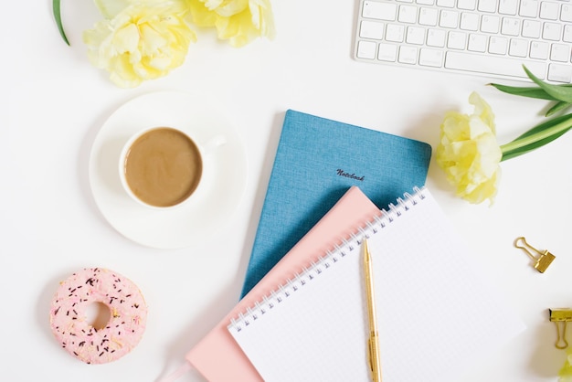 Cuaderno para la planificación diaria con desayuno servido en una taza de fondo blanco de flores de donut de café