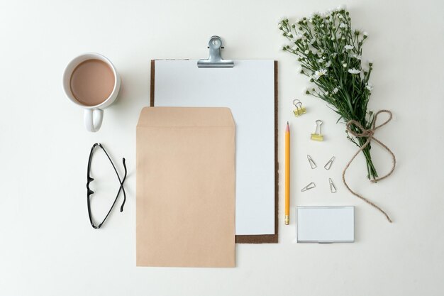 Cuaderno plano sobre fondo blanco con hojas de verano y otros artículos de papelería en un estilo moderno