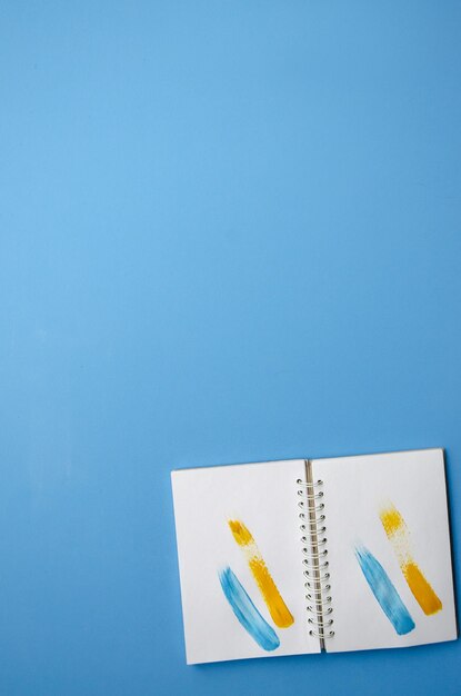 Foto cuaderno plano vertical abierto con trazos amarillos y azules sobre fondo azul