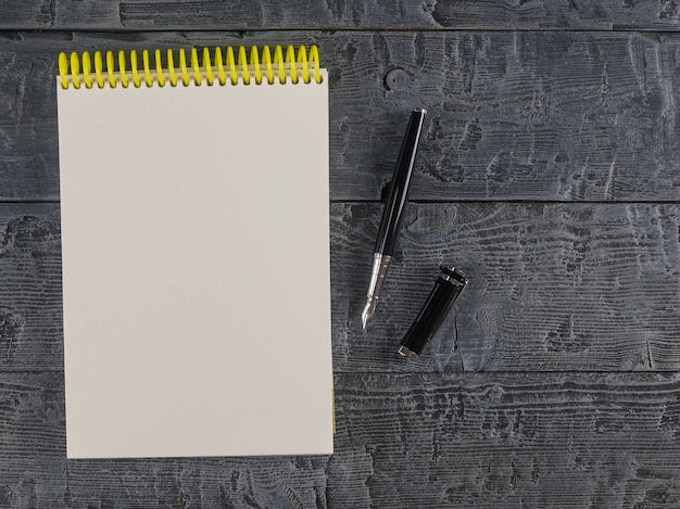 Cuaderno y pluma estilográfica en una vista superior de la mesa oscura. Lugar para su texto.