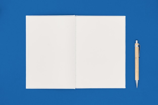 Foto cuaderno y pluma sobre fondo azul. lista de deseos o concepto de objetivos. vista superior, plano, copia espacio. color de moda del año 2020.