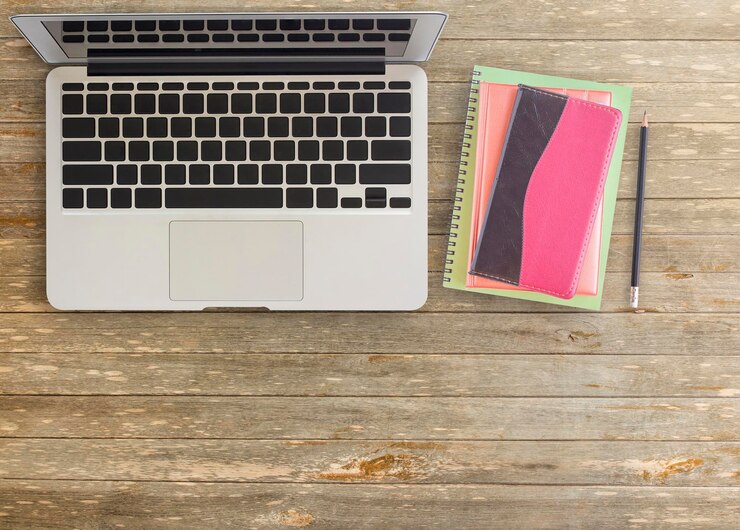 Foto cuaderno y portátil con lápiz sobre mesa de madera