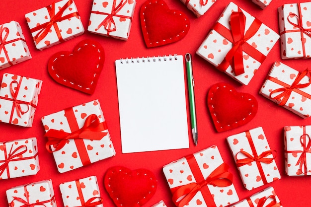 Foto cuaderno rodeado de cajas de regalo con corazones de papel de regalo y corazones textiles