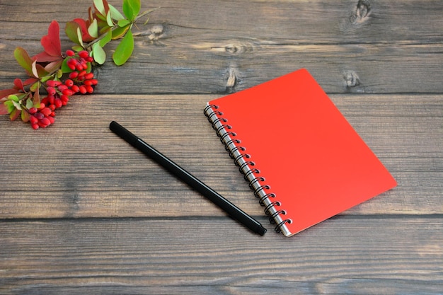 cuaderno rojo con bolígrafo negro sobre fondo de madera aislado, primer plano