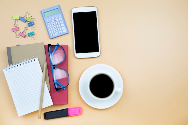 Cuaderno rojo cubierta teléfono móvil calculadora y café negro taza blanca azul gafas