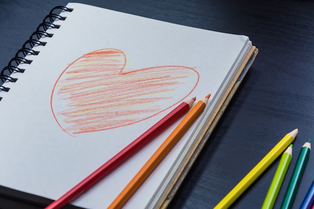 Foto cuaderno sobre el escritorio, dibujo de corazón sobre el cuaderno.