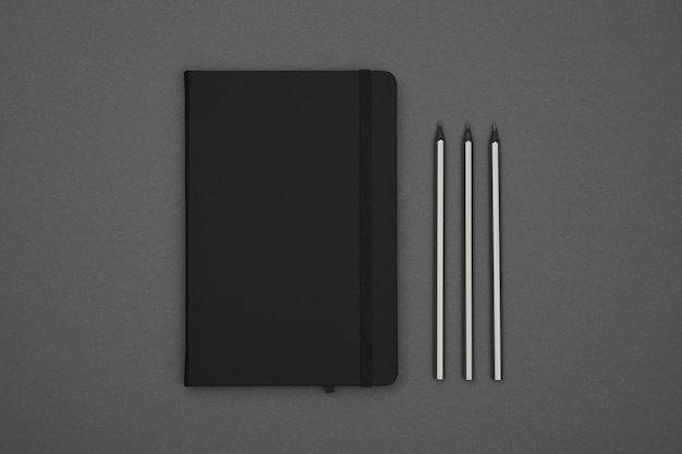 Cuaderno de tapa de cuero negro plano sobre gris