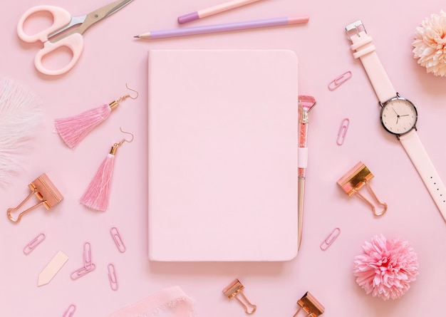 Cuaderno de tapa dura y accesorios escolares rosa en rosa pastel Maqueta de libro de texto de vista superior Lugar de trabajo femenino con tijeras, lápices, bolígrafos, clips, pendientes y reloj Concepto de regreso a la escuela