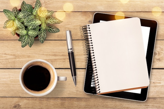 Cuaderno y taza de café fuerte sobre fondo de madera.