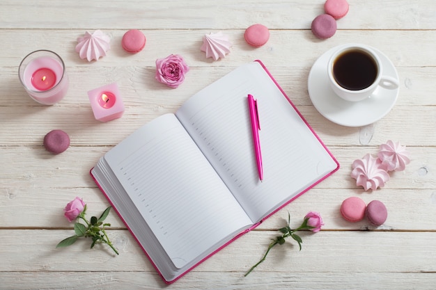 Cuaderno con taza de café en la mesa de madera blanca