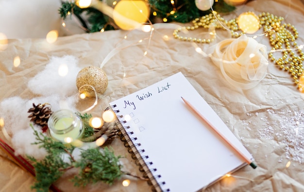 Foto cuaderno con texto mi lista de deseos 2021 decoración navideña dorada cinta de luces de año nuevo rama de abeto