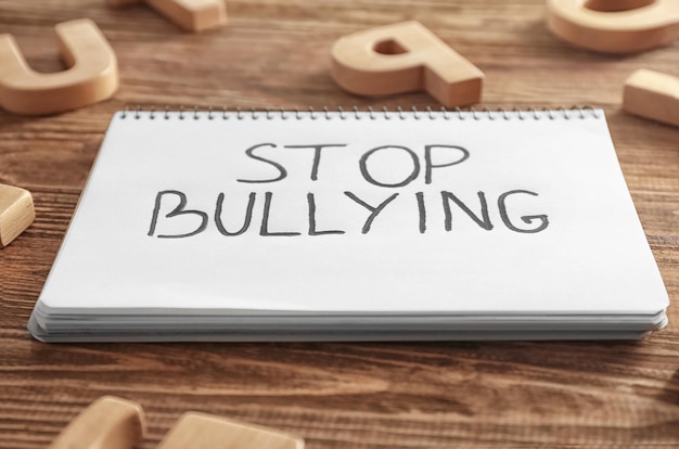 Cuaderno con texto Stop bullying en primer plano de fondo de madera