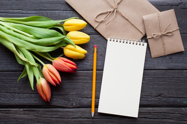 Cuaderno vacío, lápiz y tulipanes amarillos.