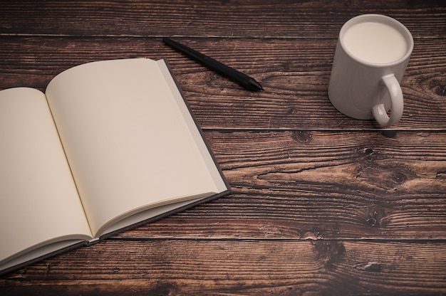 El cuaderno y un vaso de leche están sobre el escritorio.