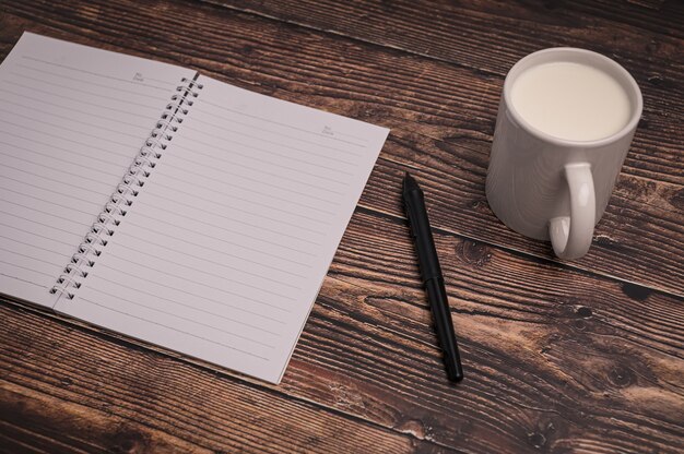 El cuaderno y un vaso de leche están sobre el escritorio.