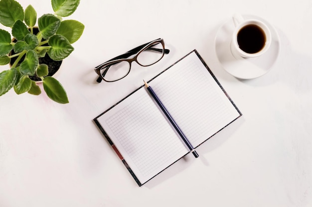 Cuaderno con vasos y café en la mesa.