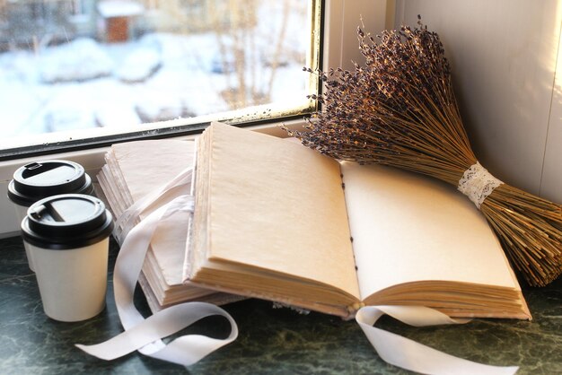 Cuaderno vintage en alféizar de mármol verde abierto con páginas en blanco y un montón de lavanda