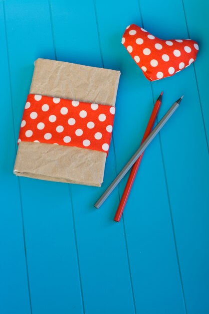 Cuaderno vintage, corazón con lunares rojos y lápices de madera.